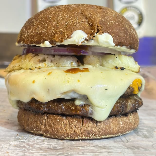 Hambúrguer alto com queijo derretido, registrado no Instagram da Container