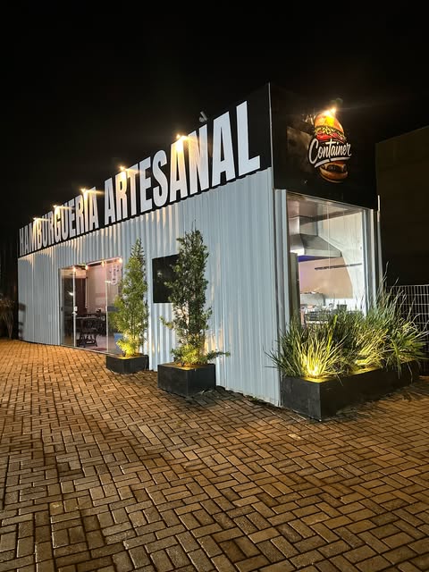 Fachada iluminada da Container Hamburgueria à noite
